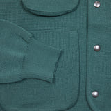 Close up: George Cardigan in Emerald made from warm merino wool. Featuring four handy storage patch pockets, a collarless neckline, and metal snap button closure.  100% merino wool.