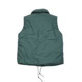 Close up: Loft Technical Nylon Vest in Emerald is a padded layering piece for extra warmth. Featuring off-centre button closure to keep the cold out, front slash pockets, and a miniature shawl neckline that can be turned up against the elements. The waist has an adjustable drawstring for fit and to keep cosy.  100% nylon. Filling: 100% Polyamide Primaloft insulation.