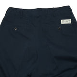 Close up: Good Basics Chinos in Dark Navy. A relaxed fit with central pleat on front and back, side slash pockets, a coin pocket, and two buttoned back pockets. Featuring belt loops and a button-fly closure. All buttons are corozo fisheye.  100% organic cotton.  Made in Portugal.
